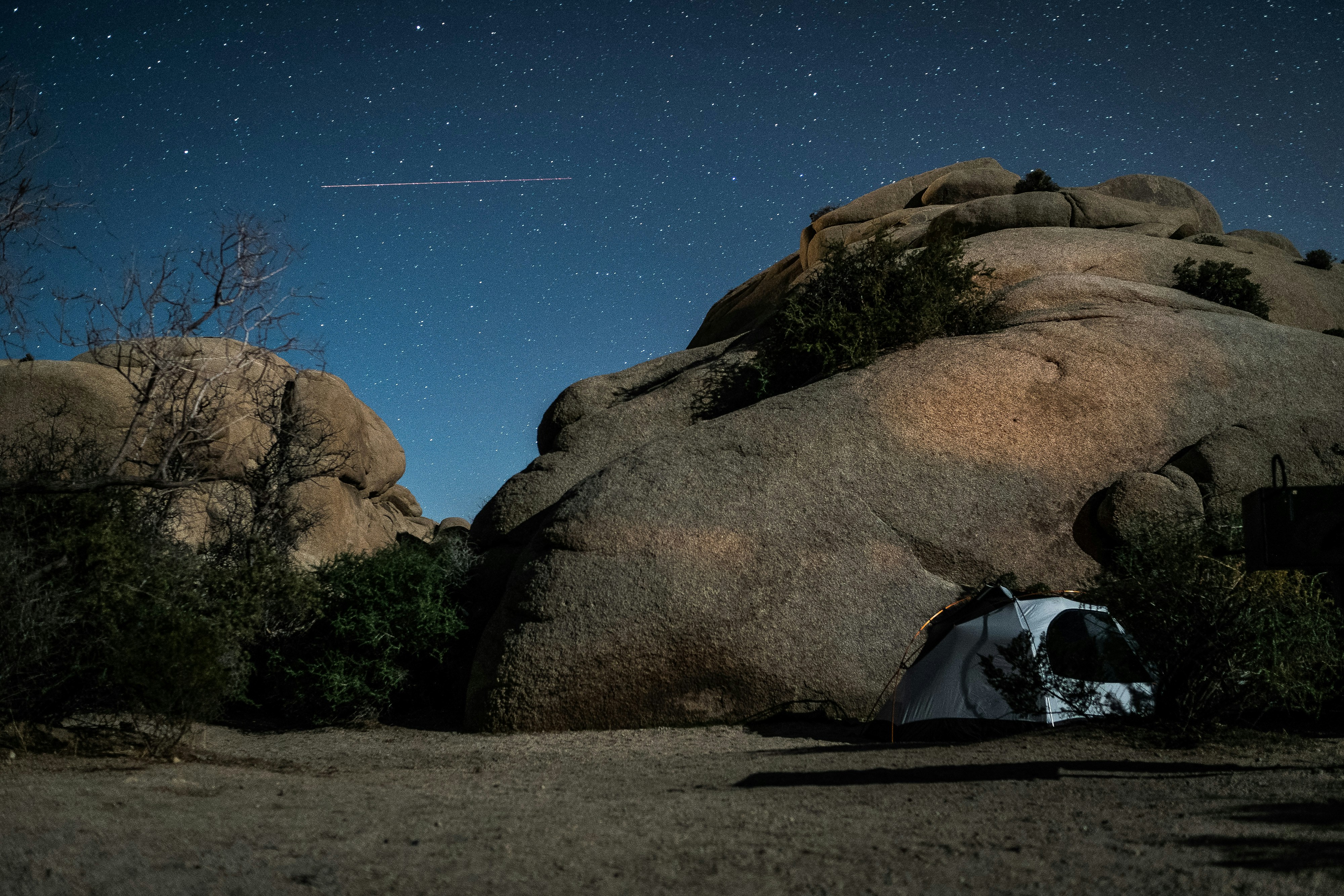 Camping in Jumbo Rocks against a starry night sky.