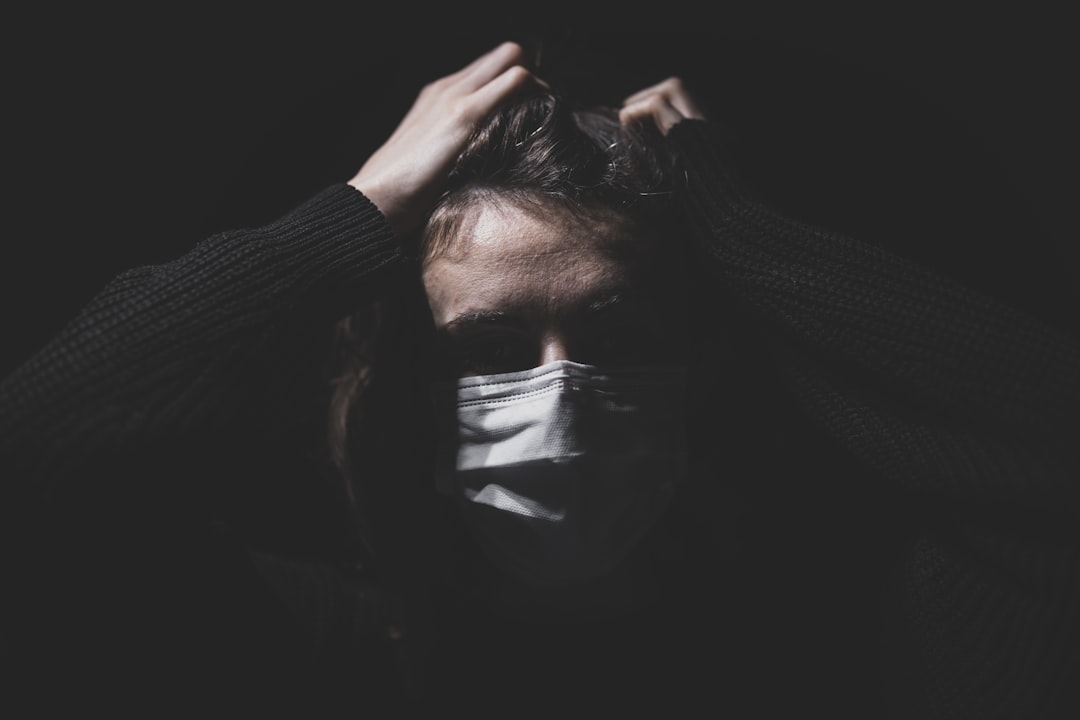 woman in black long sleeve shirt covering face with hands, pandemic and stress