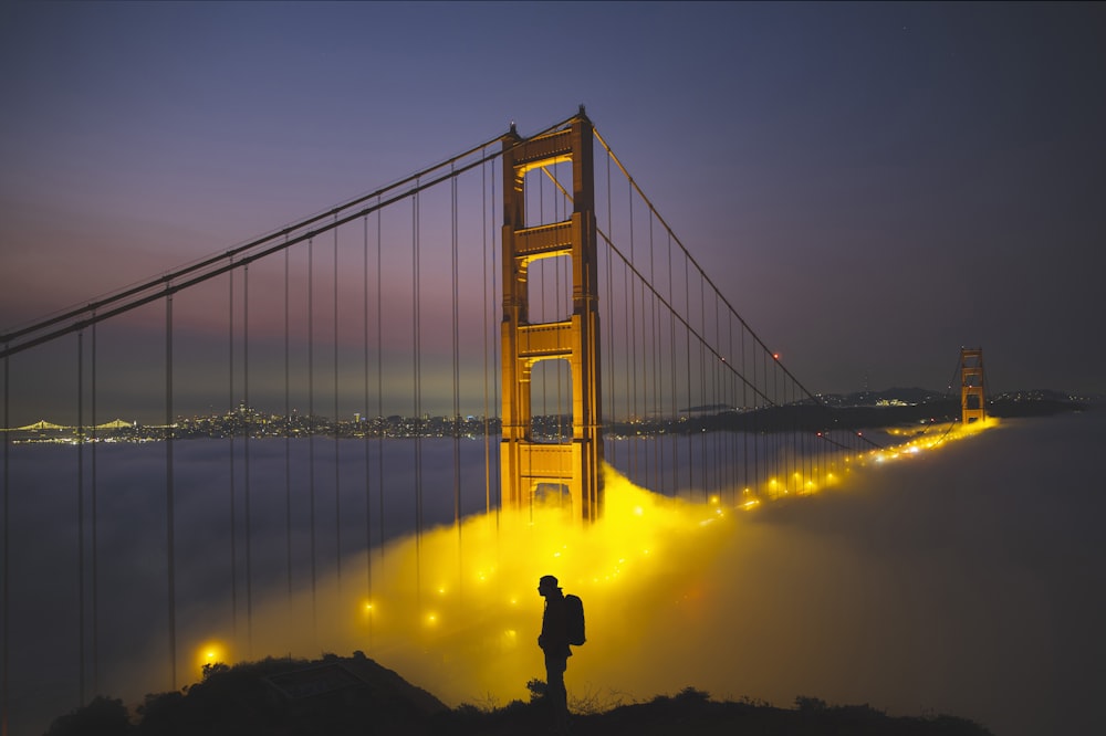 silhouette of man standing on bridge during night time