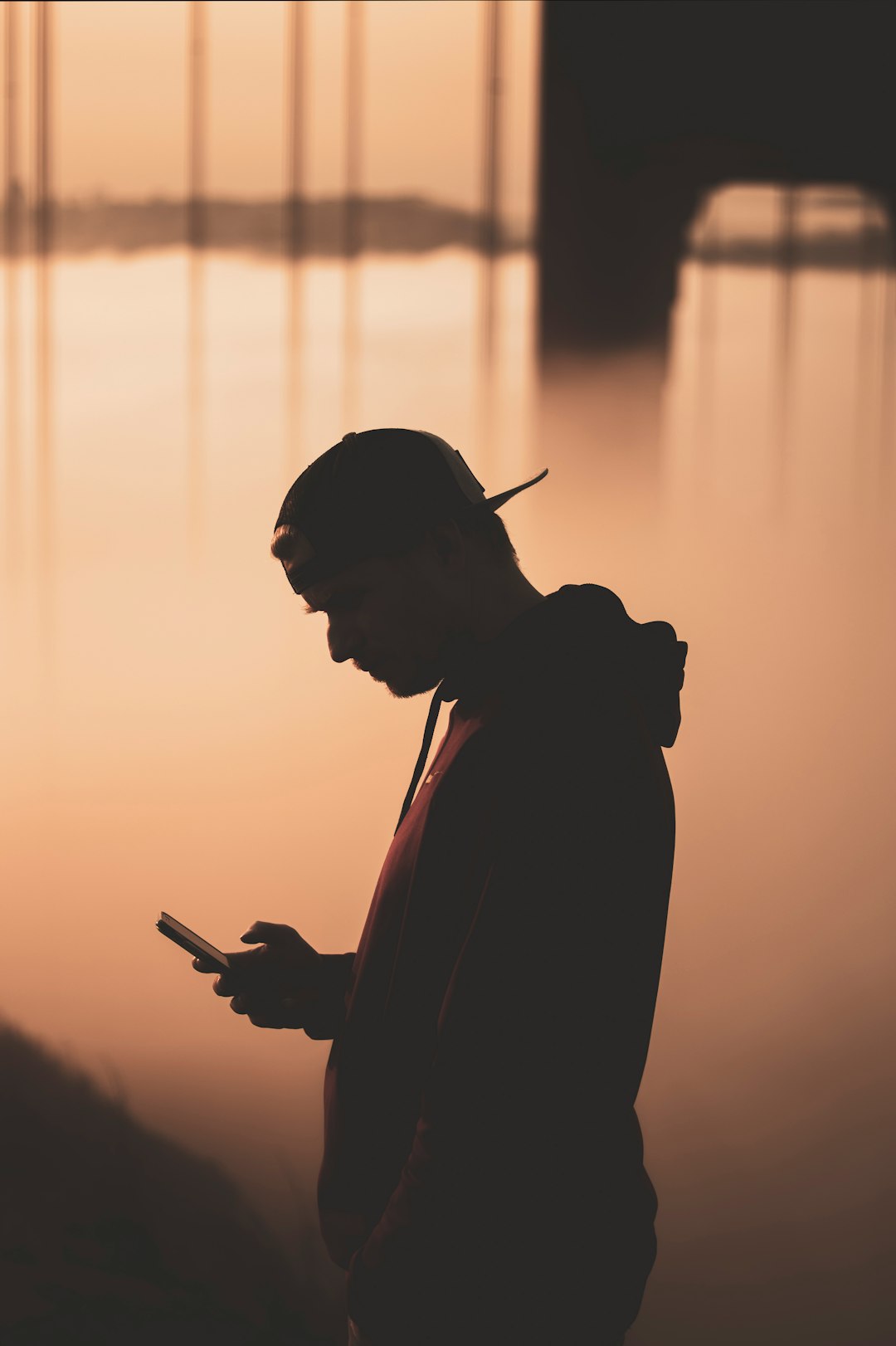 silhouette of man holding smartphone during sunset