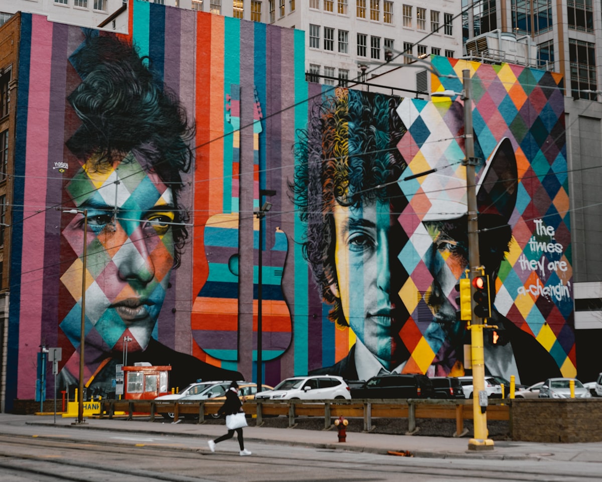 Mural of a building with 3 different eras of Bob Dylan's face with the quote "The times they are a-changin"