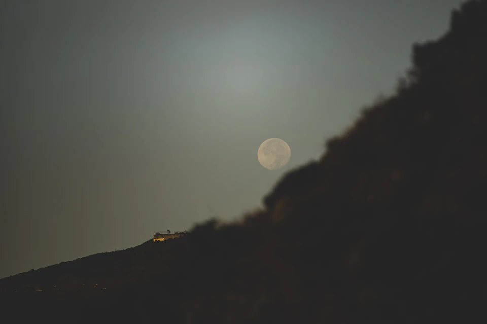Serene night scene with full moon casting soft glow on surrounding landscape below