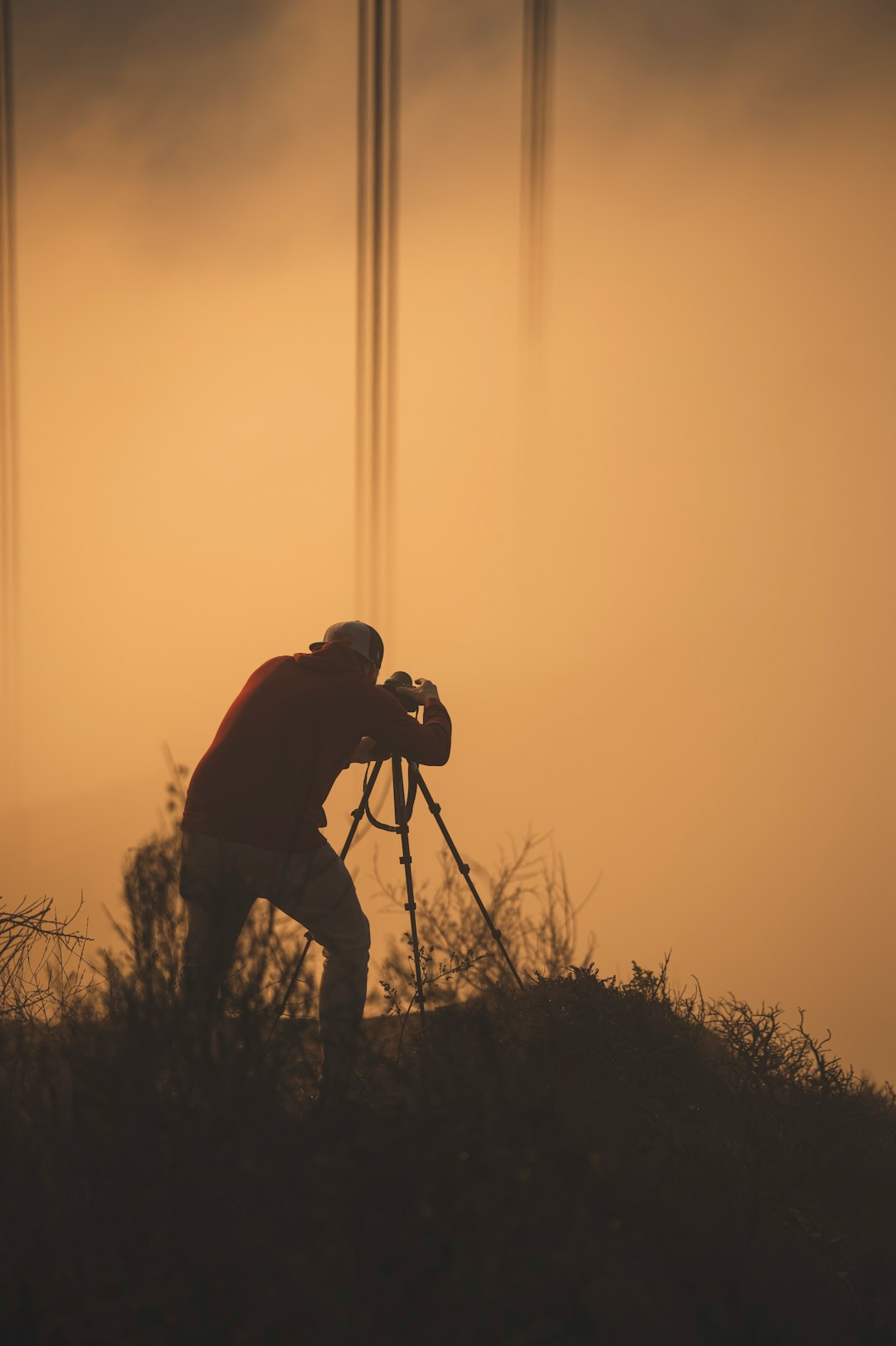 silhouette of man holding camera during sunset