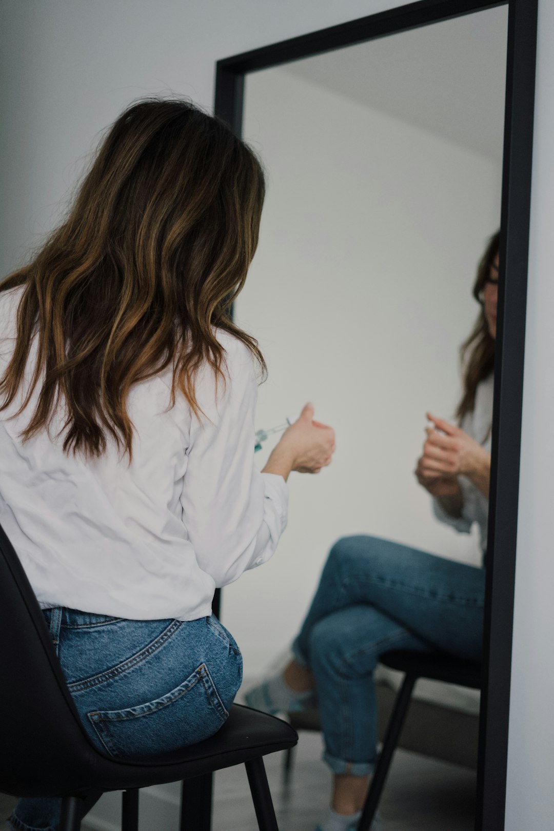 woman in white long sleeve shirt and blue denim jeans sitting on chair