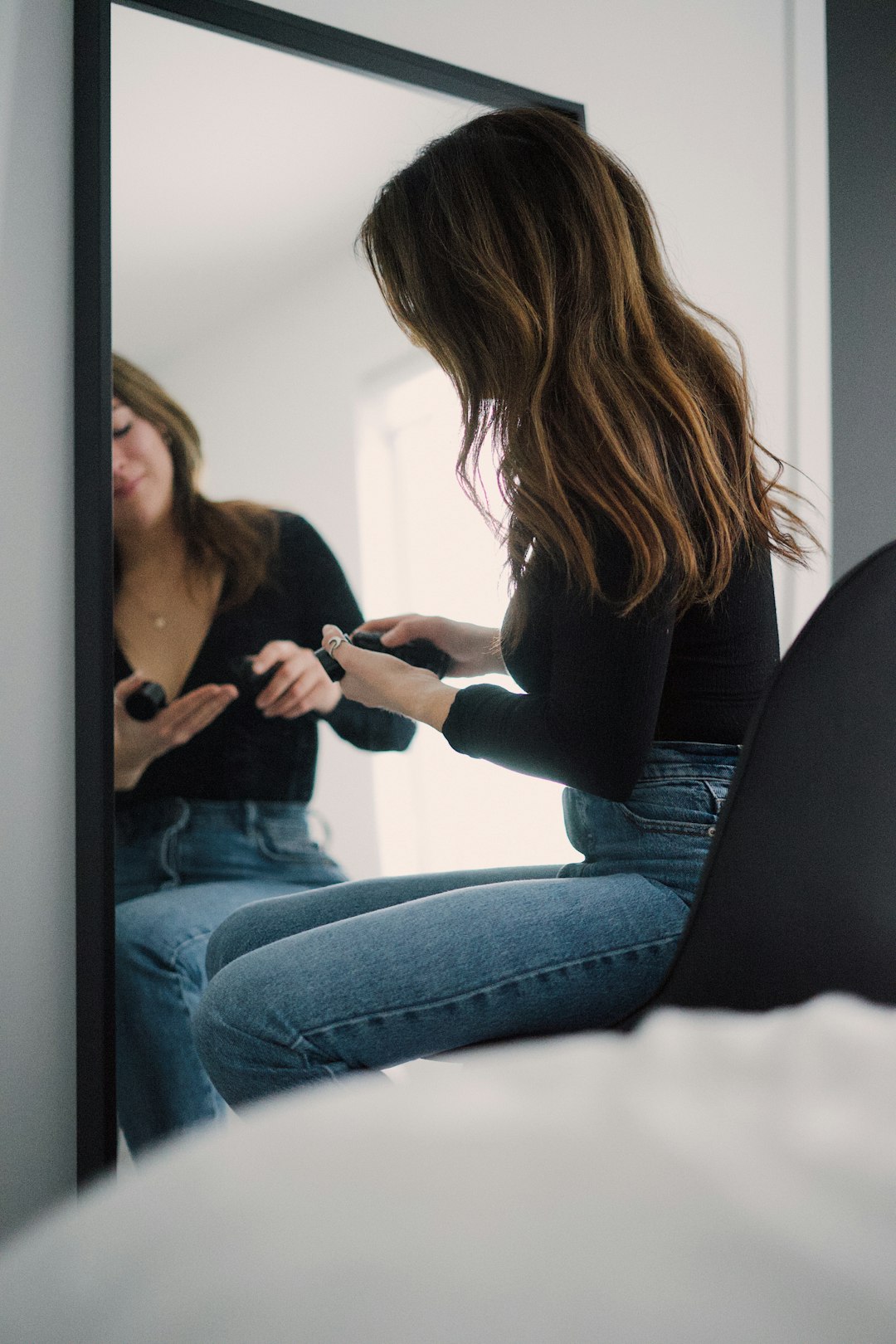 woman in black long sleeve shirt and blue denim jeans sitting on black sofa