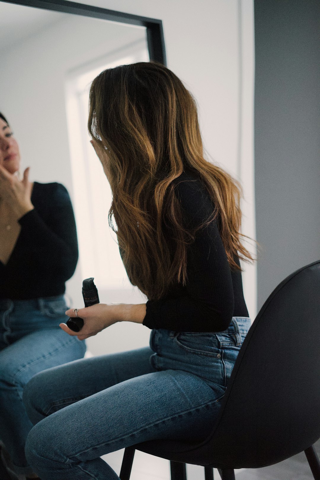 woman in black long sleeve shirt and blue denim jeans sitting on chair