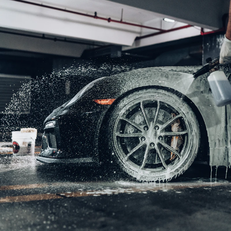 Car being hand-washed with professional detailing soap and microfiber mitt