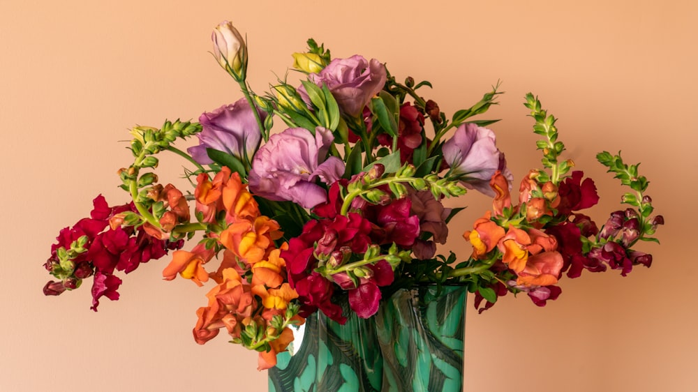 pink and yellow flowers in green glass vase