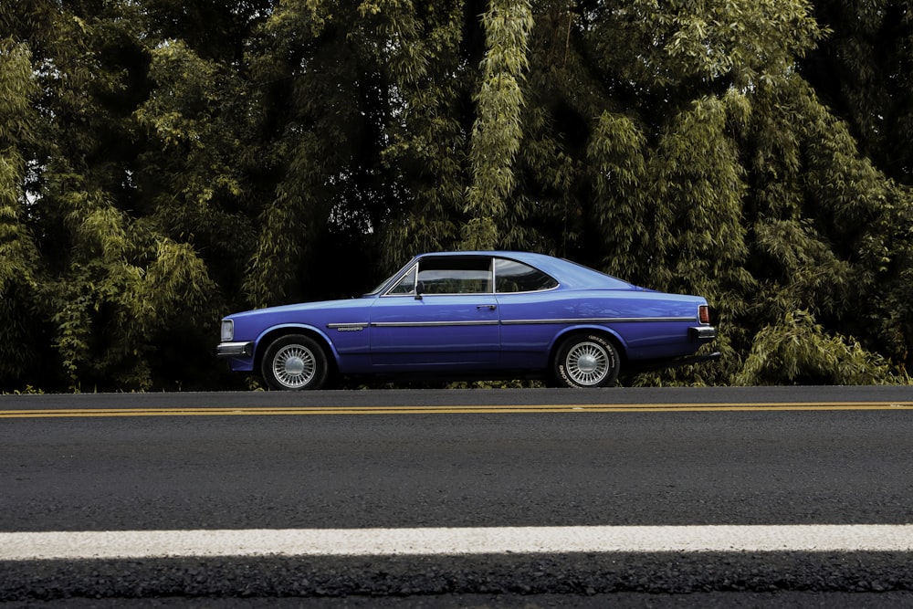 cupé azul en una carretera de asfalto gris durante el día