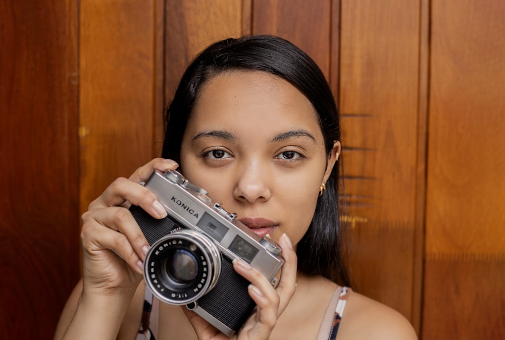 woman in white tank top holding gray and black camera