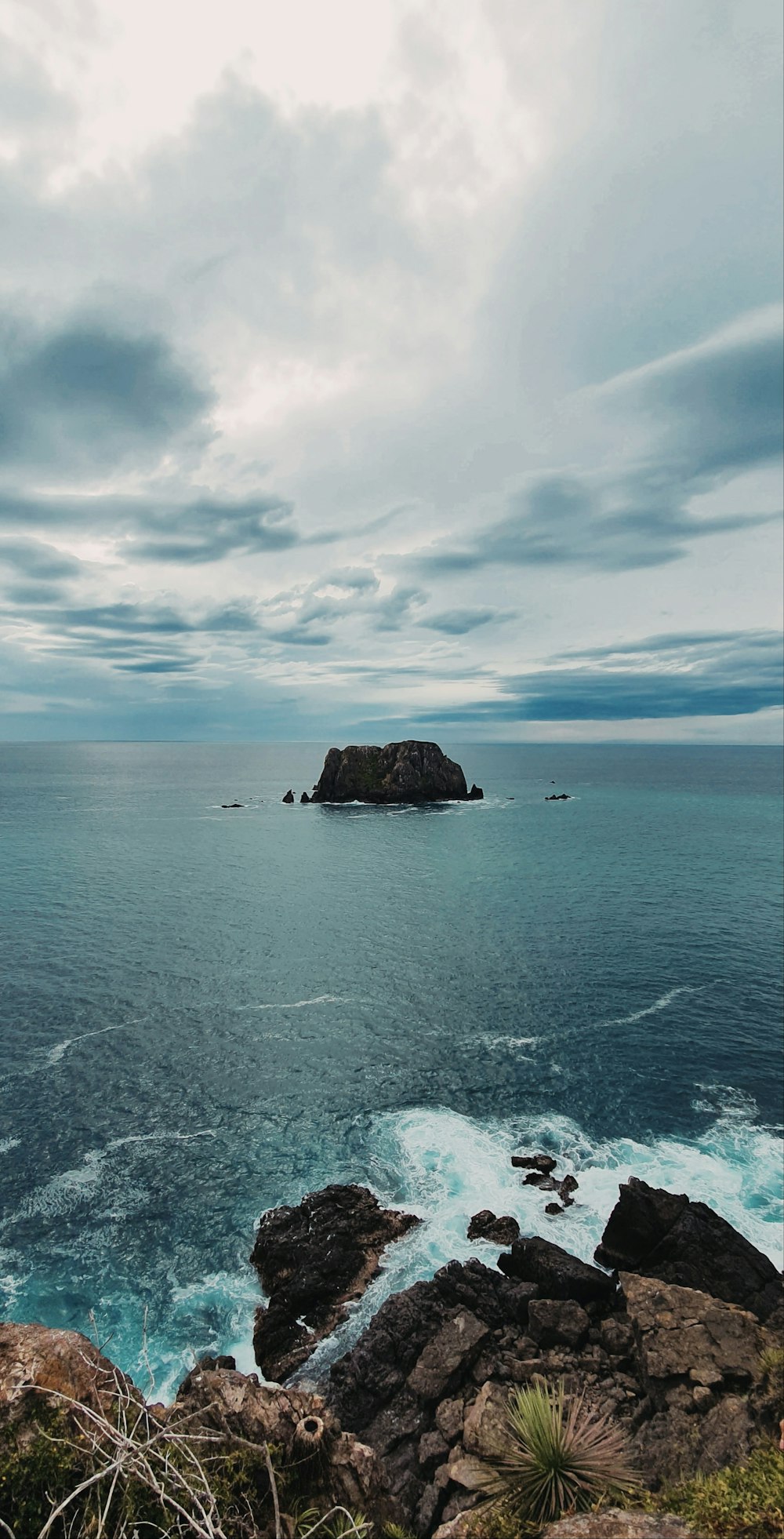 brown rock formation on sea under white clouds during daytime