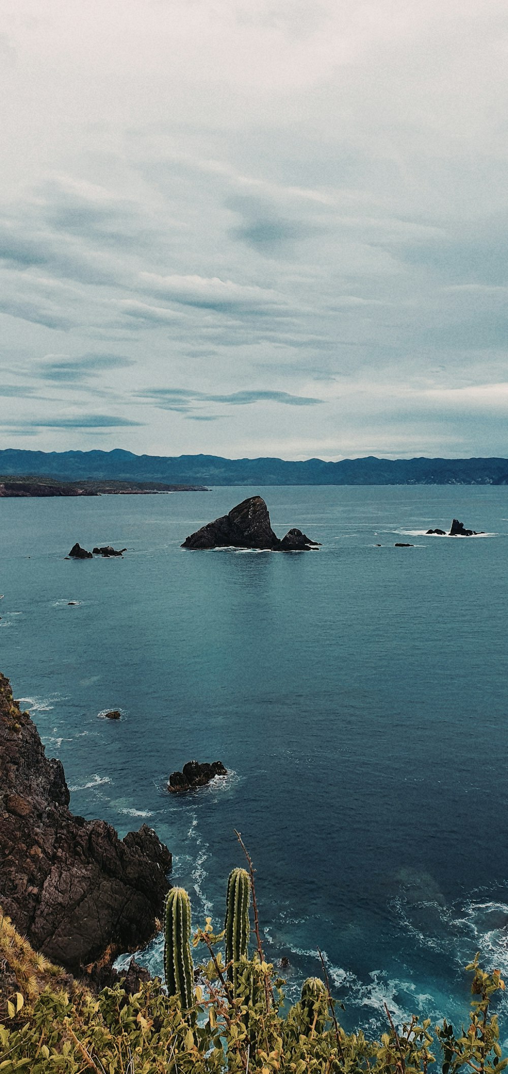 black rock formation on sea under blue sky during daytime