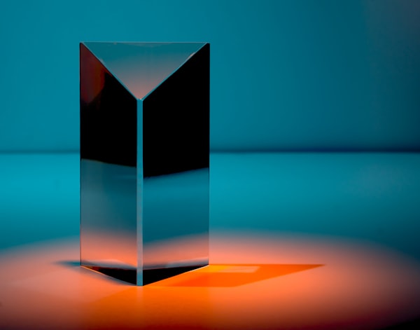 a dark and reflective triangular column on a colored surface
