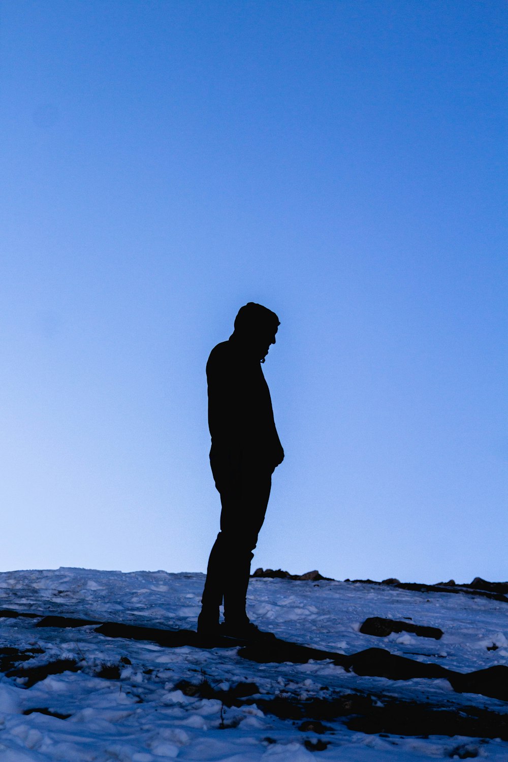 silhouette of man standing on rock formation during daytime