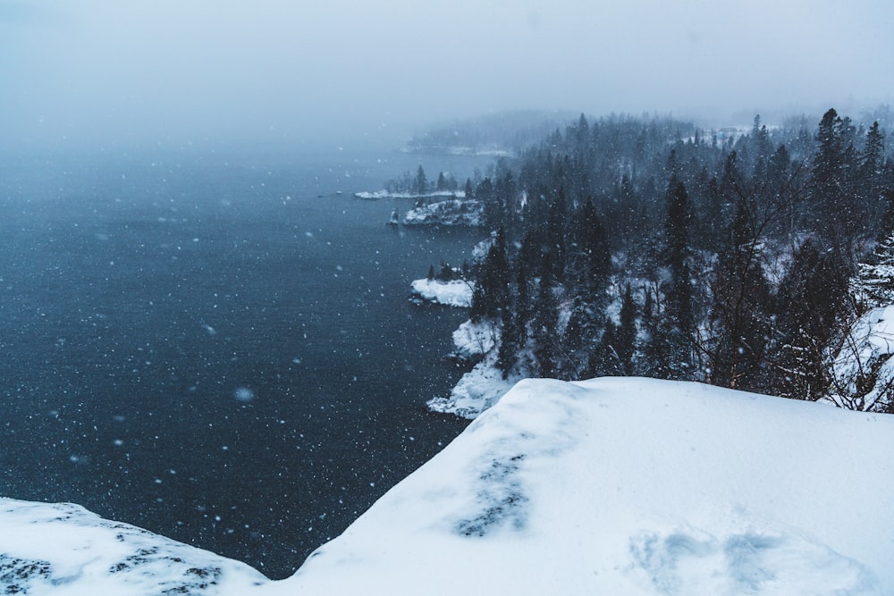 snow covered mountain near body of water during daytime