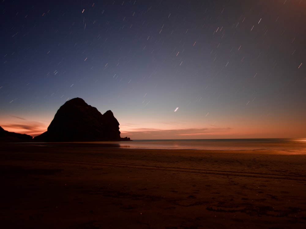 silhouette of mountain on beach during sunset