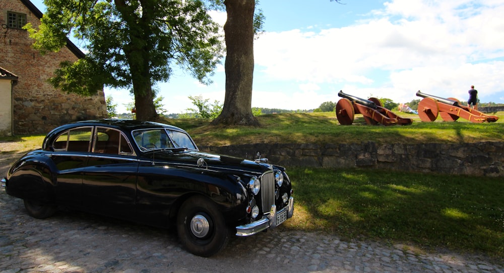 black vintage car parked beside tree during daytime