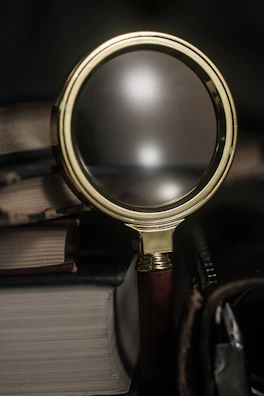 A close-up of a vintage magnifying glass over a blurred crime scene photo.