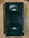 A black VHS tape lies on a wooden surface. The tape has a worn appearance with specific instructions written on it, such as 'insert this side into recorder' and 'do not touch the tape inside'.