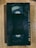 A black VHS tape lies on a wooden surface. The tape has a worn appearance with specific instructions written on it, such as 'insert this side into recorder' and 'do not touch the tape inside'.