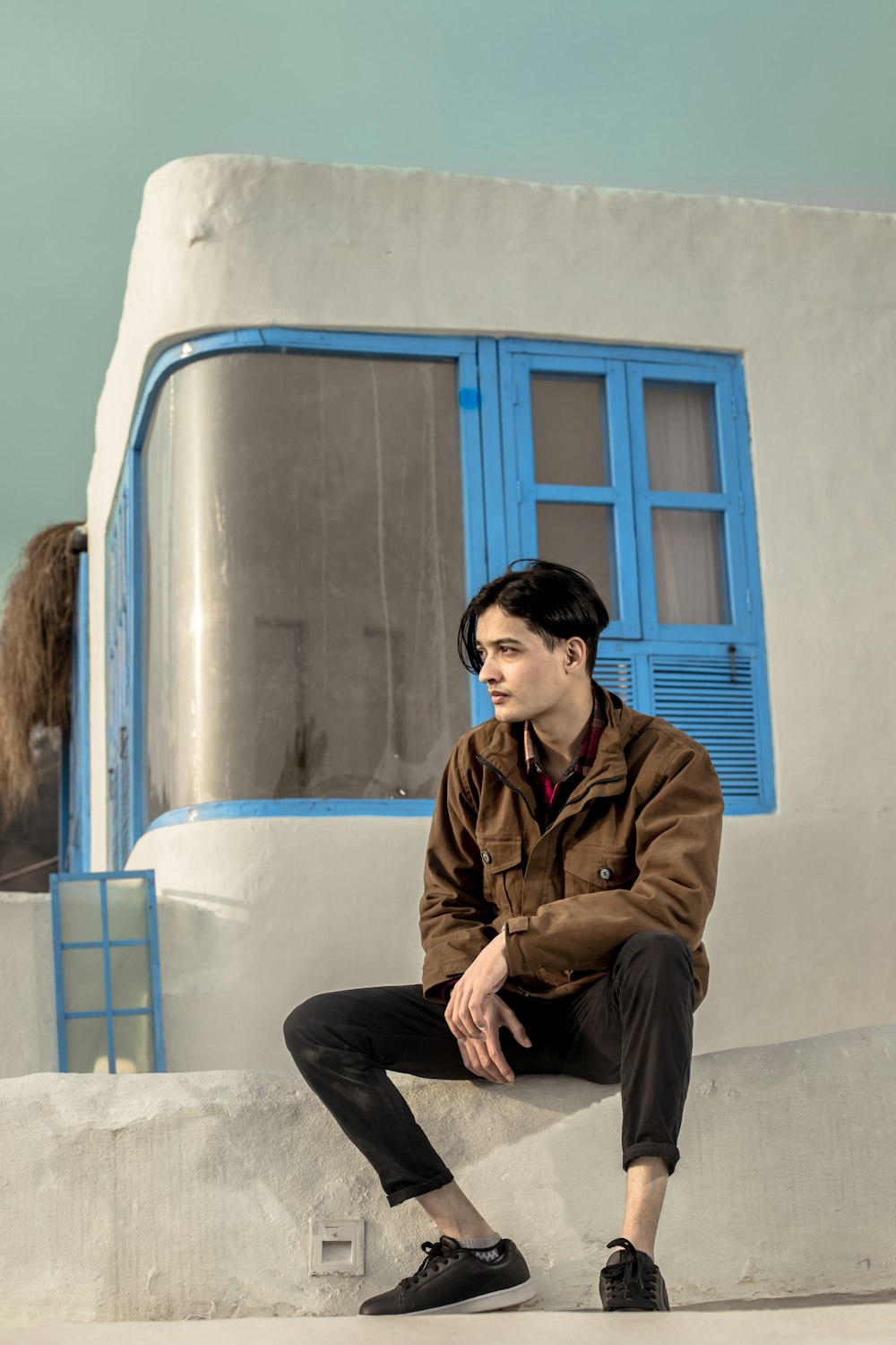 man in brown jacket sitting on blue and white train