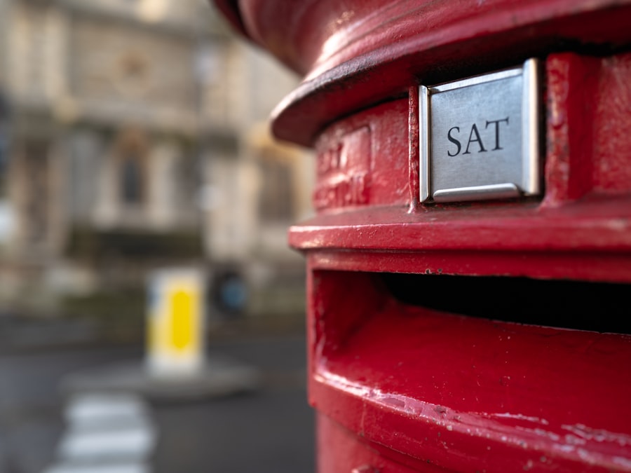 Close-up of a red Royal Mail pillar box on a London street, showing the letter slot and Saturday collection plate