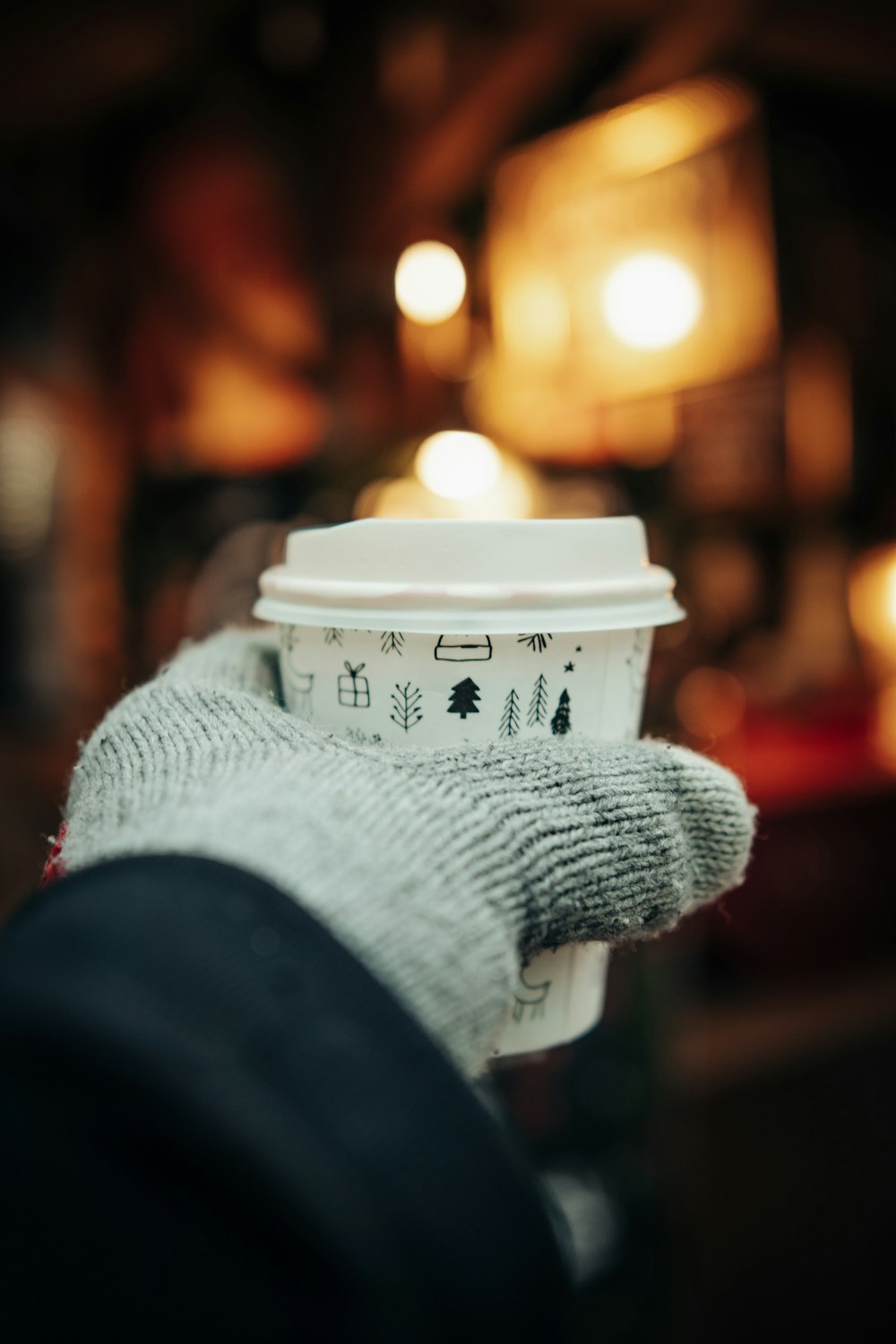 person in gray knit sweater holding white cup