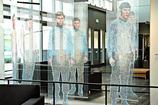man in white and blue long sleeve shirt standing near glass window