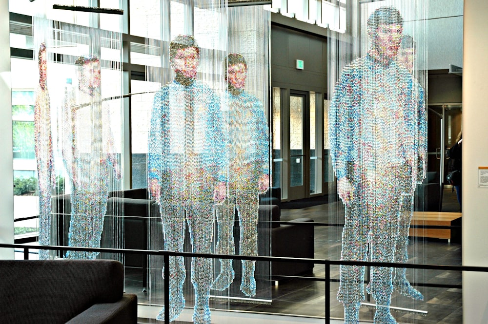 man in white and blue long sleeve shirt standing near glass window