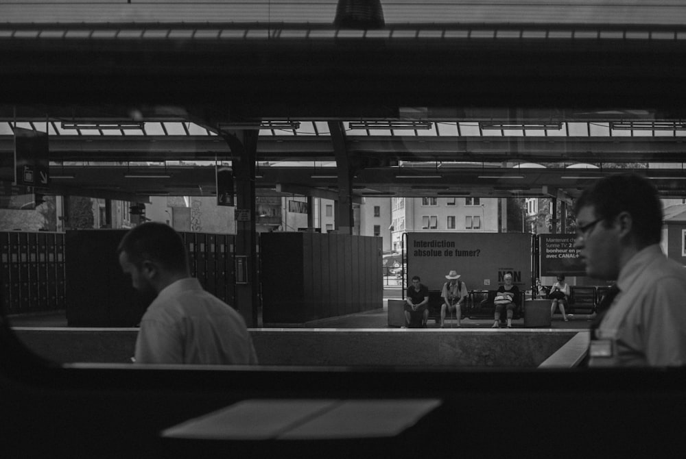 grayscale photo of man in white dress shirt sitting on bench