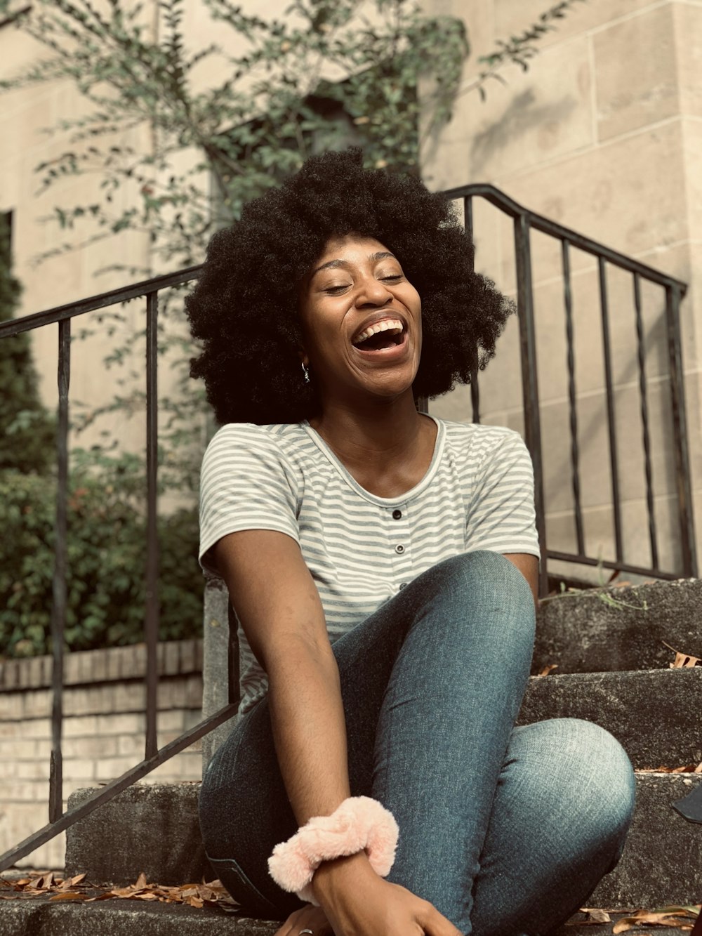 woman in white and gray striped shirt and blue denim jeans sitting on stairs