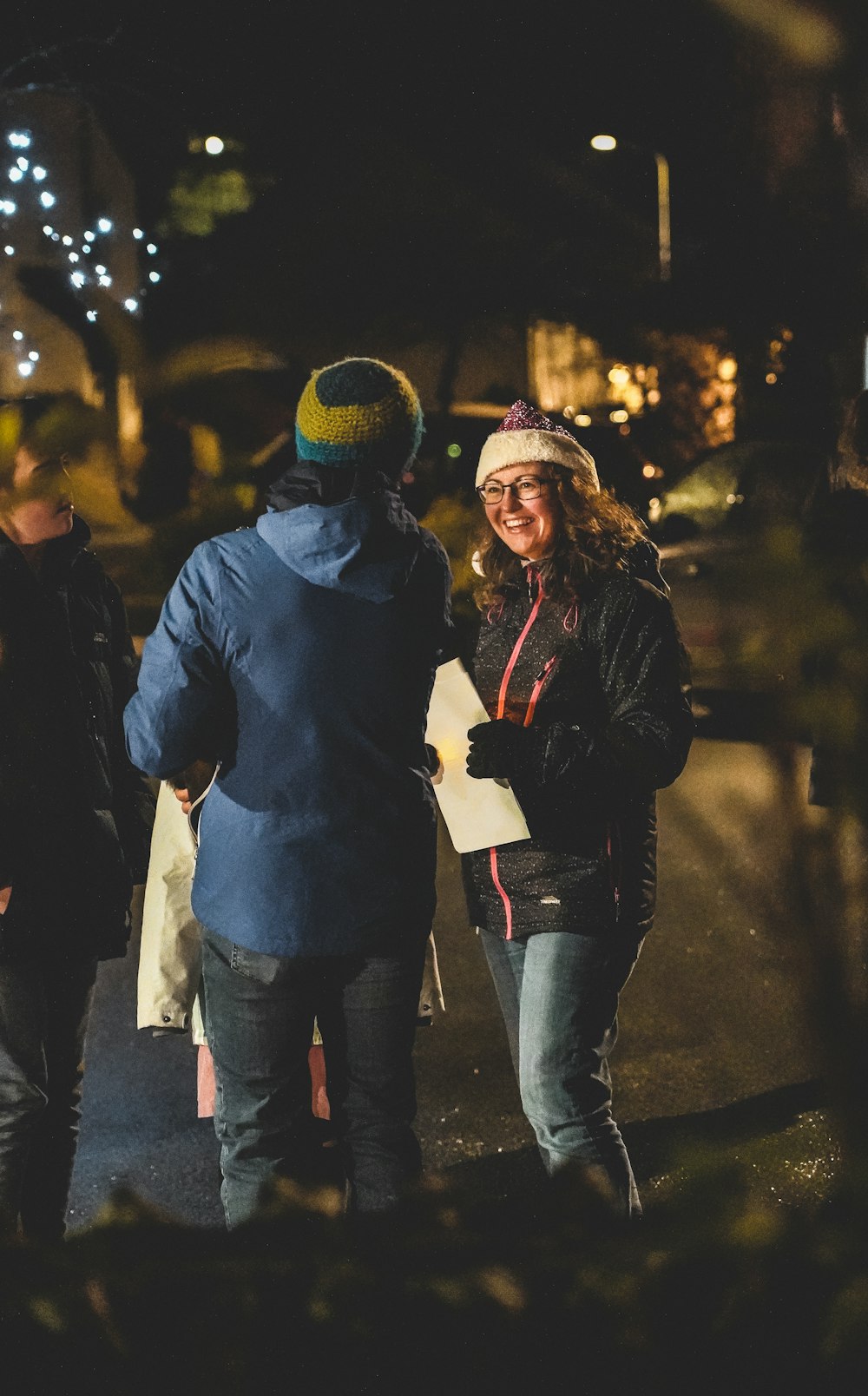 uomo e donna che indossano giacca nera e jeans blu denim che camminano per strada durante la notte