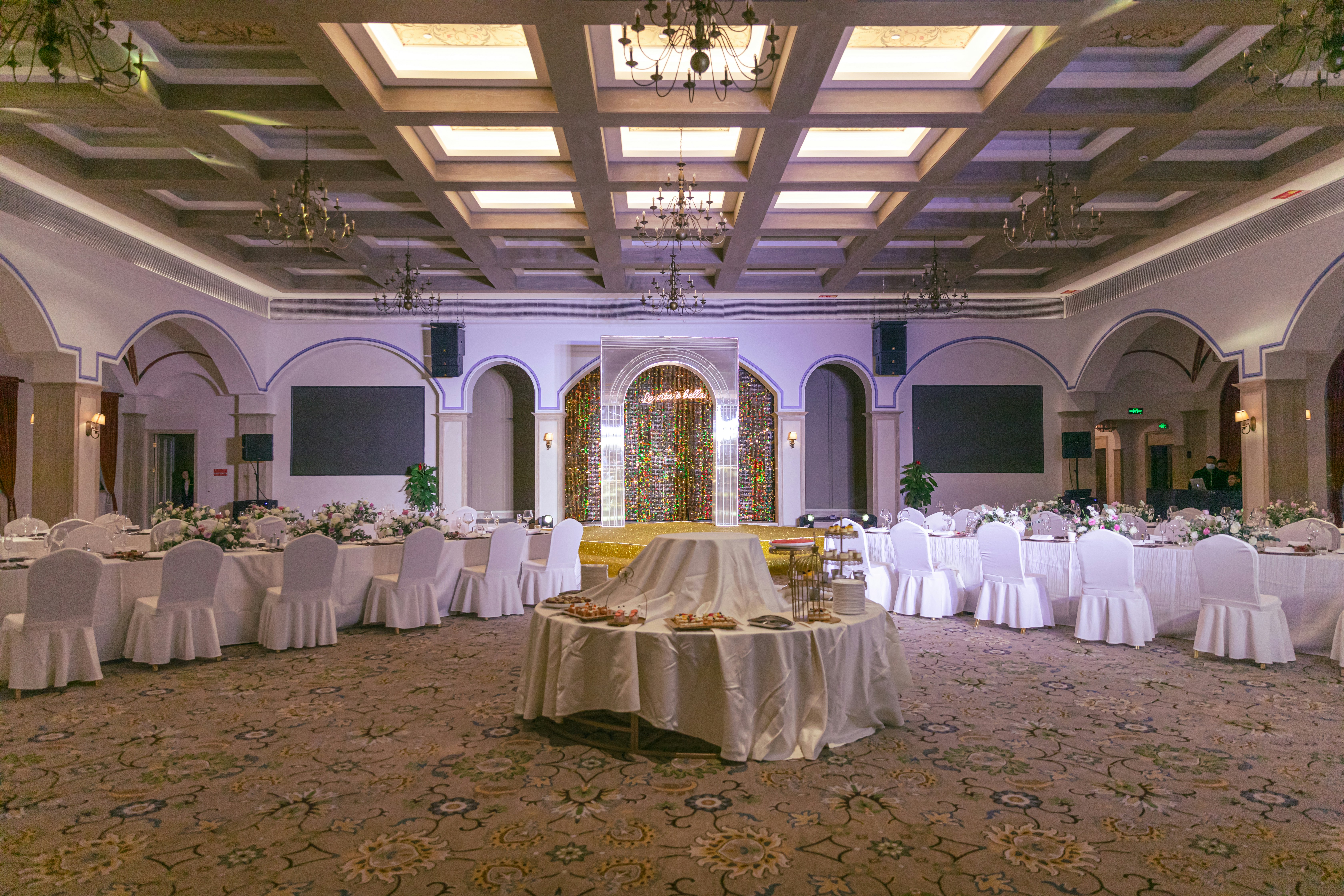 Kurumsal etkinlik salonu, beyaz çiçek aranjmanları, profesyonel masa düzeni, şık aydınlatma, temiz ve modern atmosfer