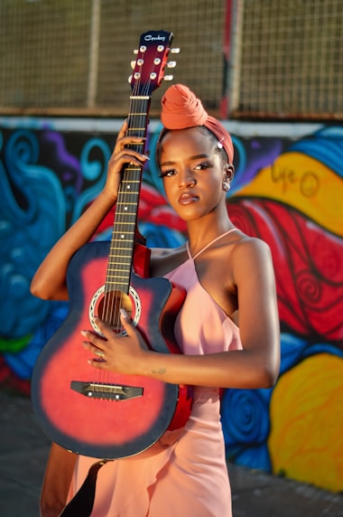 woman in red halter top playing brown acoustic guitar