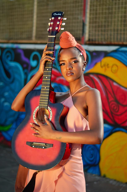 woman in red halter top playing brown acoustic guitar