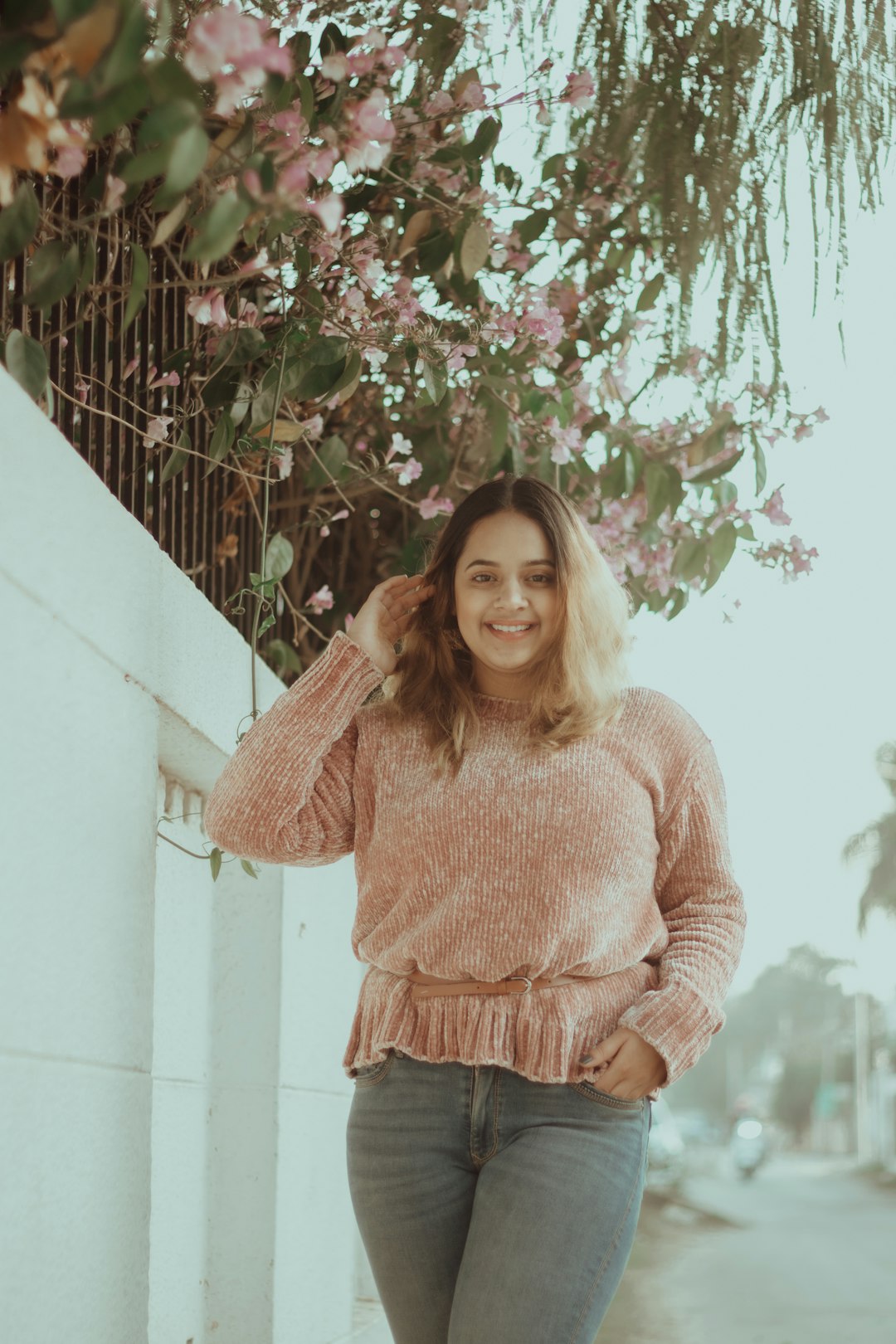 woman in brown sweater standing beside white wall