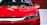 A sleek, modern car with a shiny red finish and sharp headlights. The front grille features a distinctive design with chrome accents.