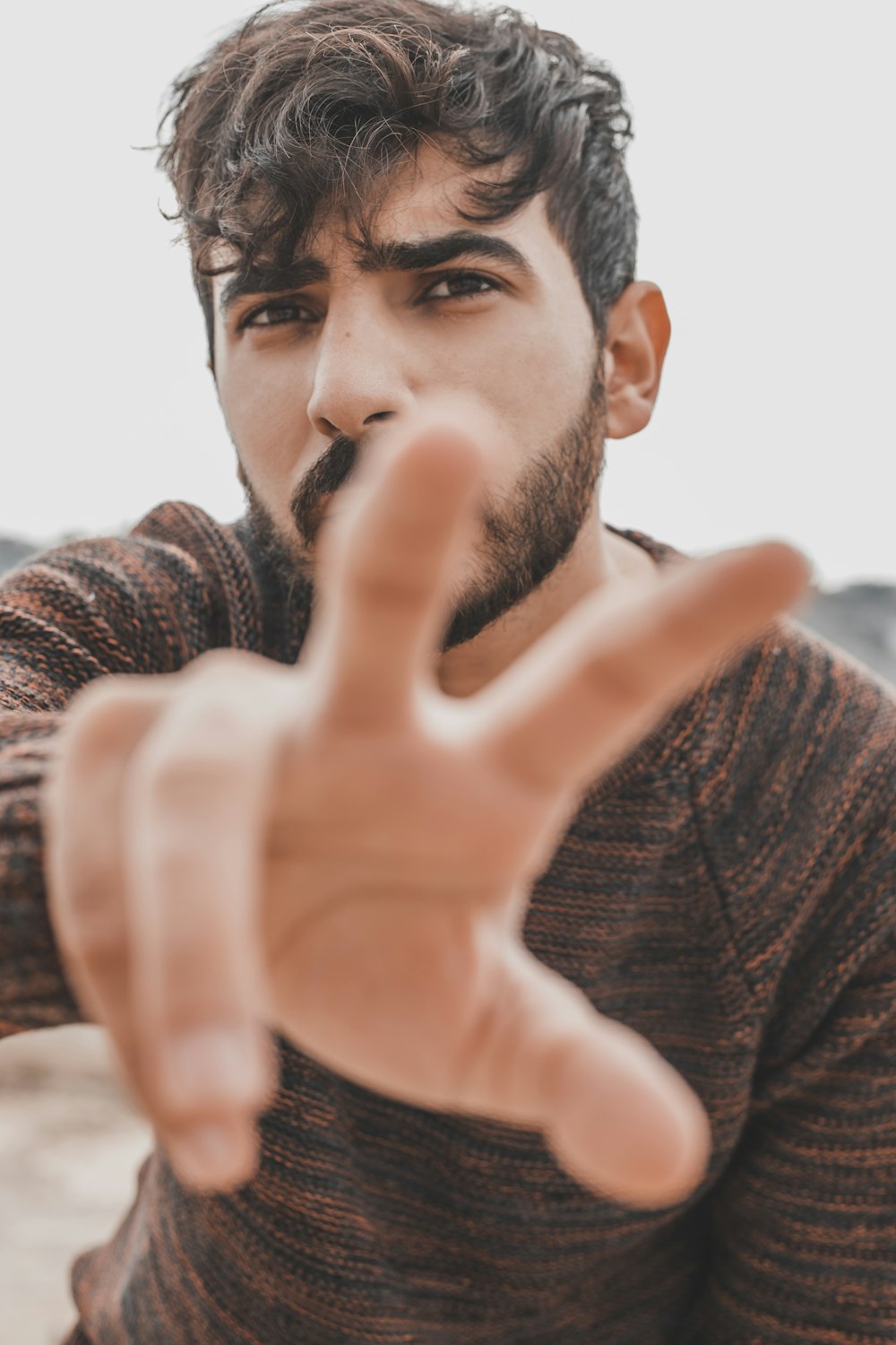 man in brown sweater holding his face