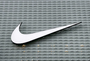 A white Nike swoosh logo mounted on a grey textured wall with repeating patterns