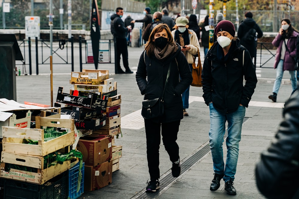 woman in black jacket and blue denim jeans walking on sidewalk during daytime