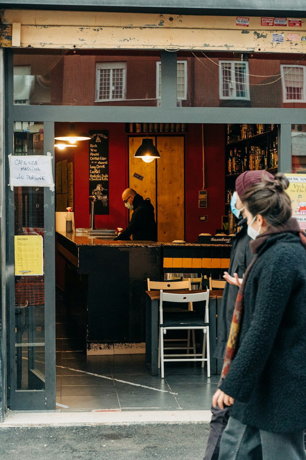 woman in gray coat standing beside brown wooden table