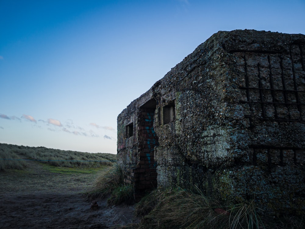 Edificio de hormigón gris cerca de campo de hierba verde bajo el cielo azul durante el día