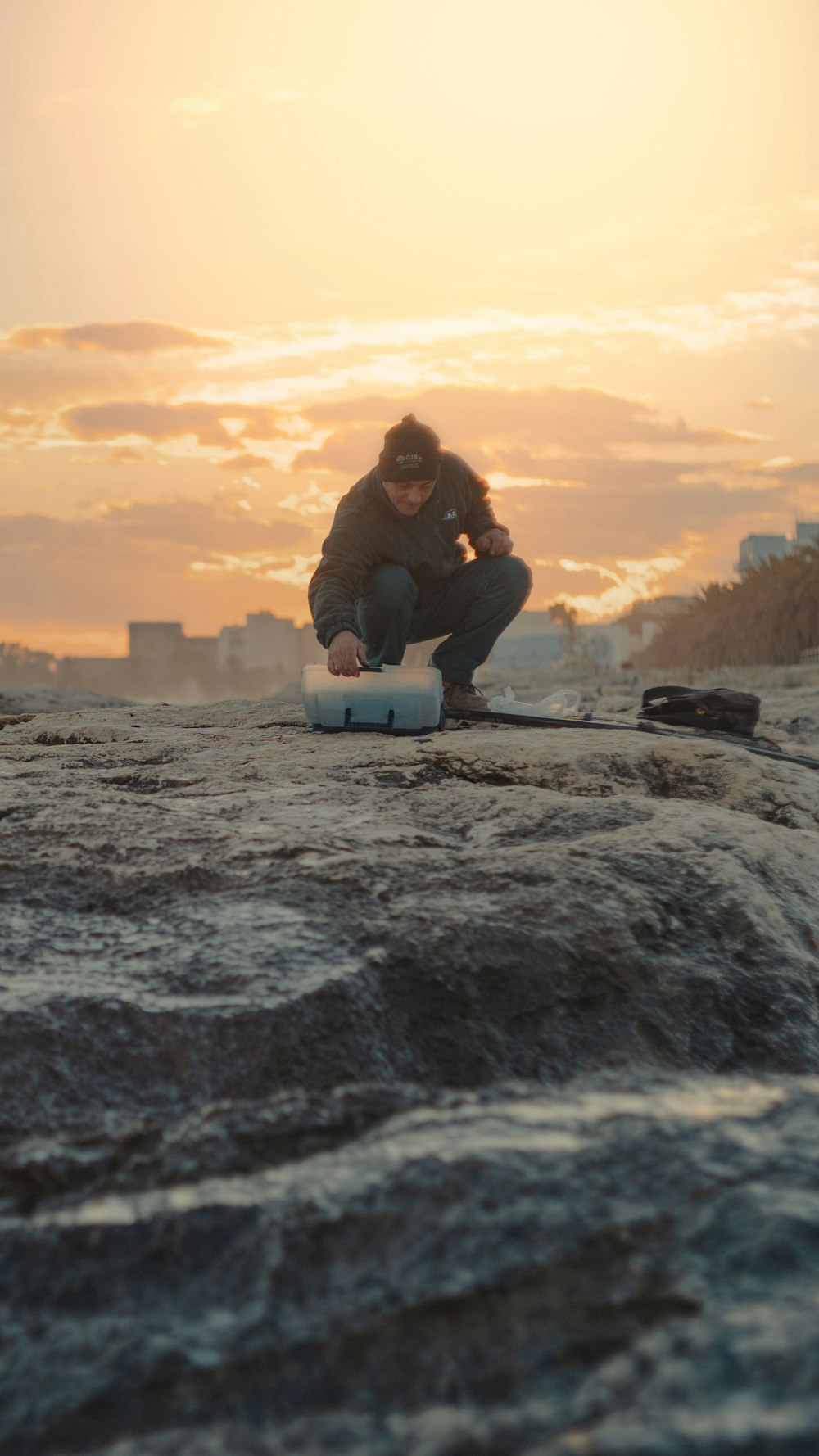 man in black jacket sitting on rock