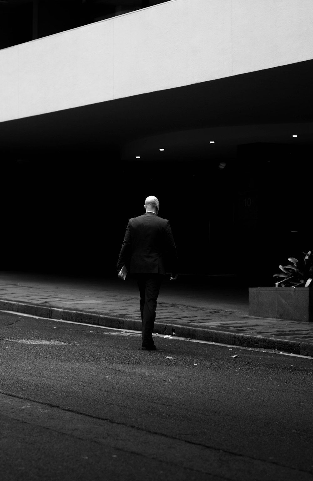 검은 코트를 입은 남자가 거리를 걷고 있다