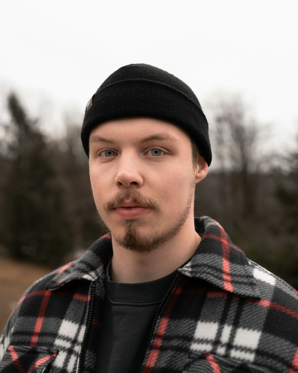 man in black knit cap and black red and white plaid jacket