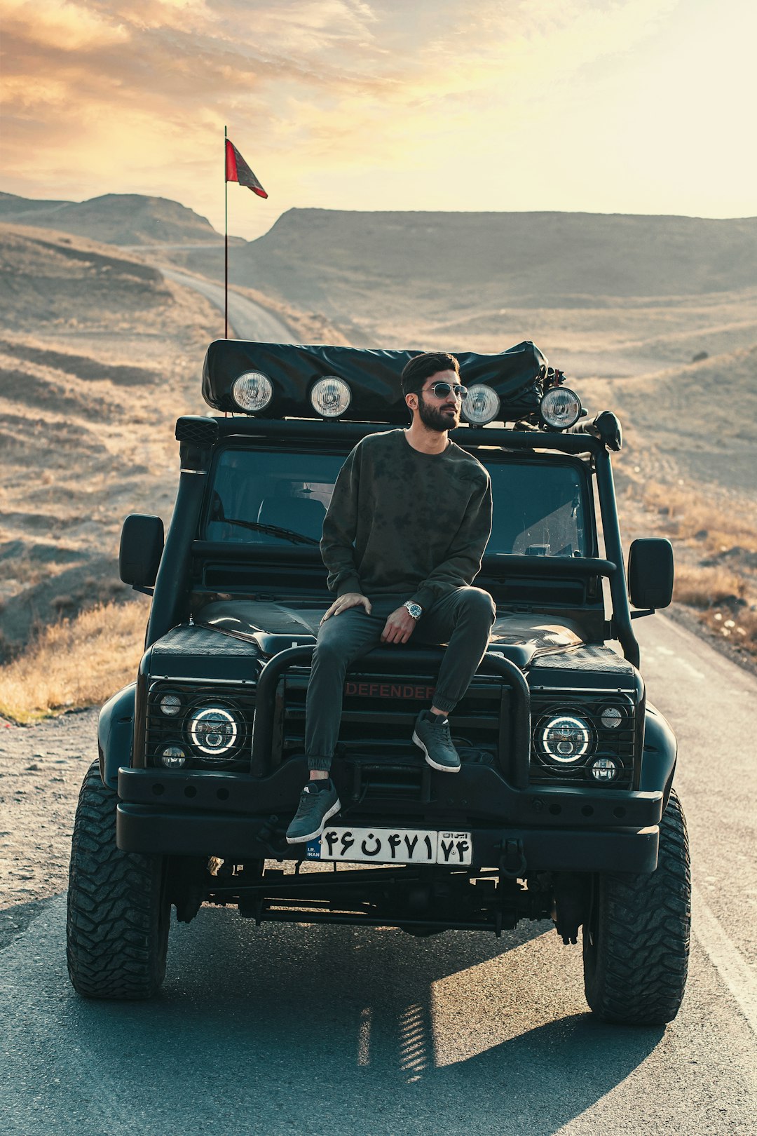 man and woman riding on black jeep wrangler on brown field during daytime