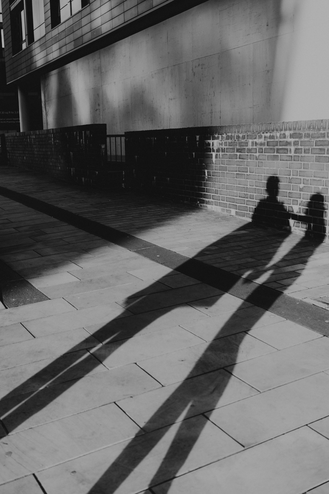 grayscale photo of man walking on sidewalk