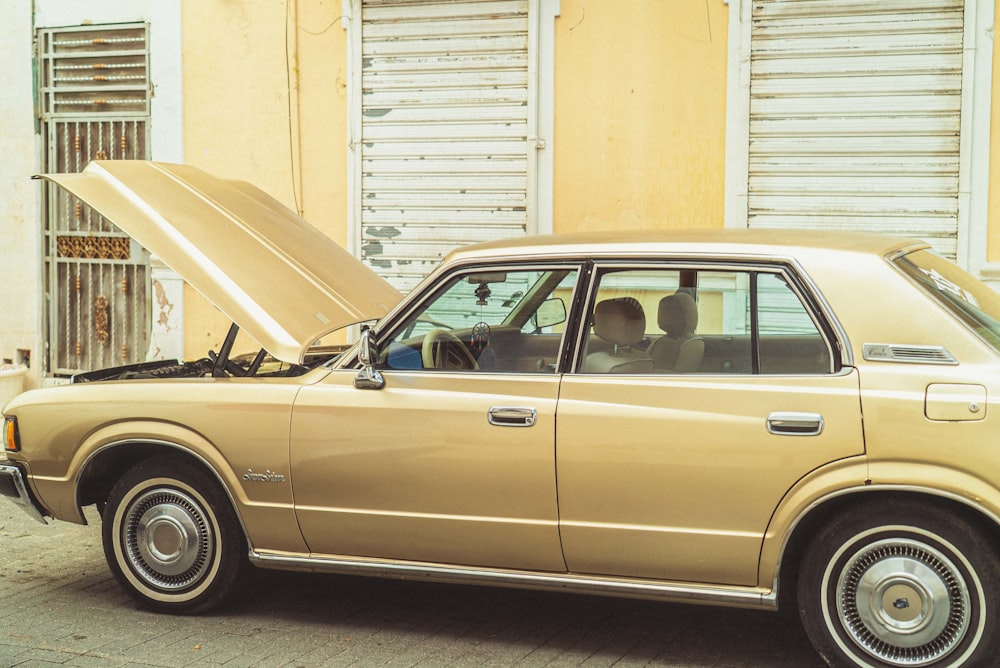 brown sedan parked beside white wall