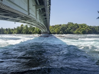 Steel framework of a bridge rising over a flowing river.