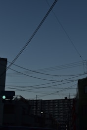 Modern energy grid with blue and green electric lines glowing over a cityscape at dusk.